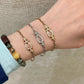 Hand wearing multiple bracelets on a neutral background