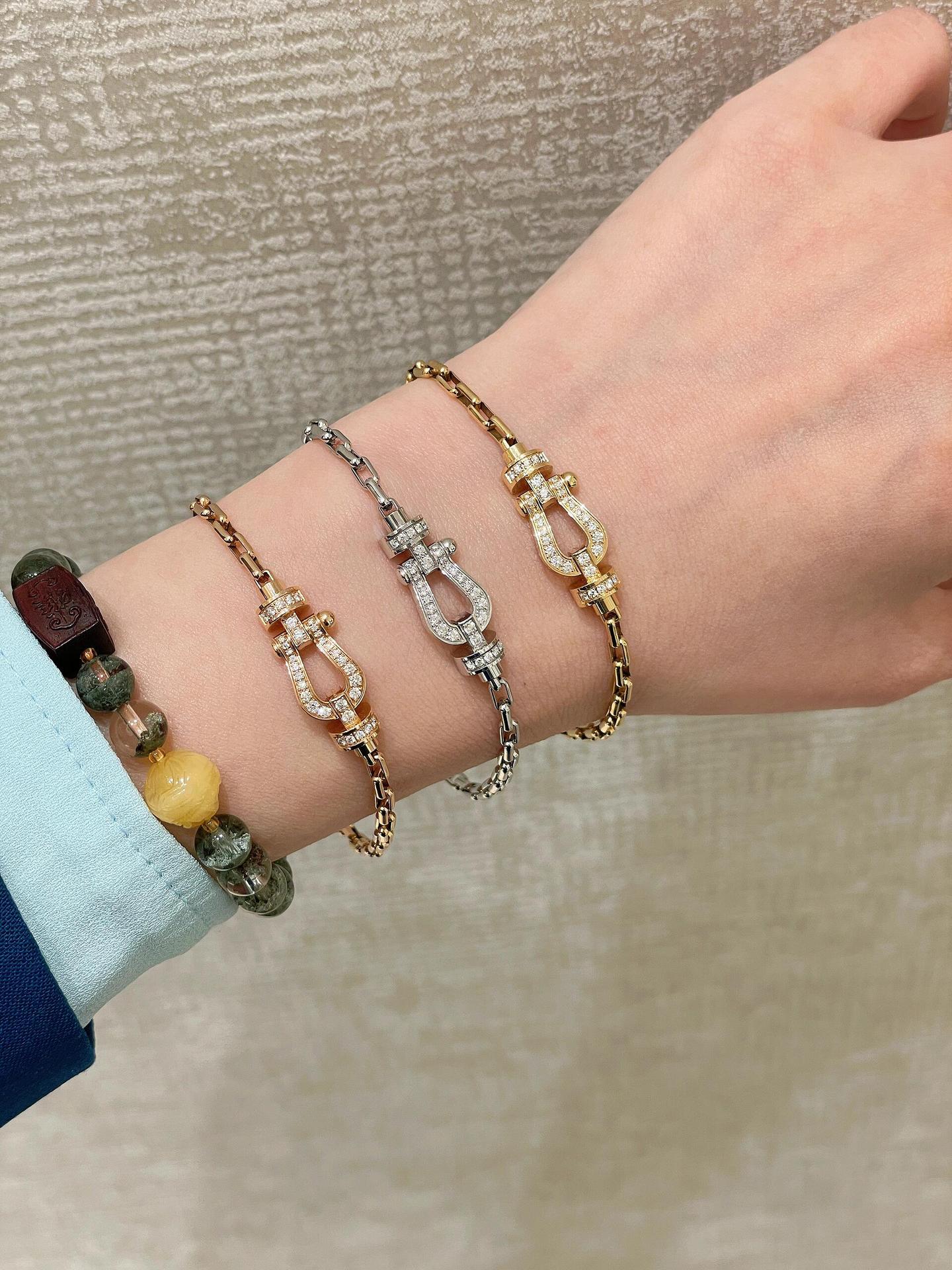 Hand wearing multiple bracelets on a neutral background