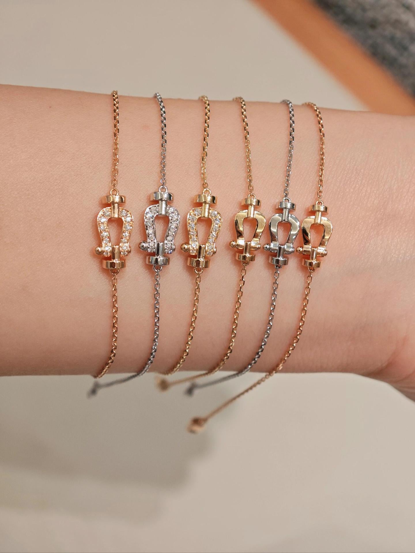 Set of gold and silver bracelets on a wrist against a neutral background