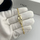 Gold bracelet on a hand wearing a white glove with 'FRED' branding in the background.