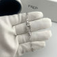 Silver bracelet on a gloved hand with 'FRED' branding in the background