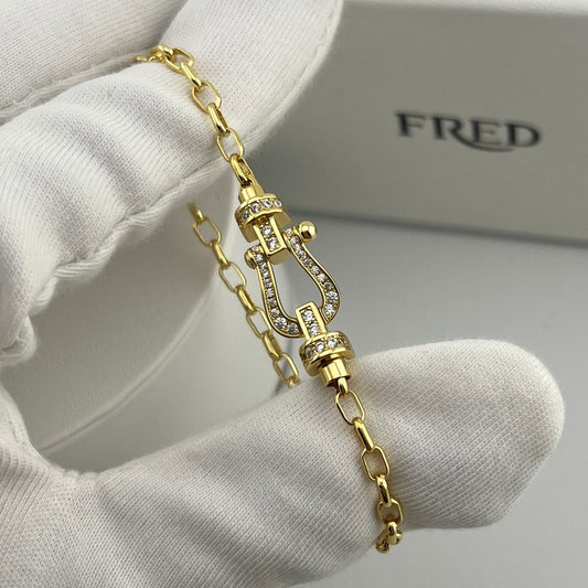 Gold bracelet with intricate design on a white surface, brand 'FRED' visible