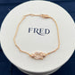 Gold bracelet on a white round display with 'FRED' branding