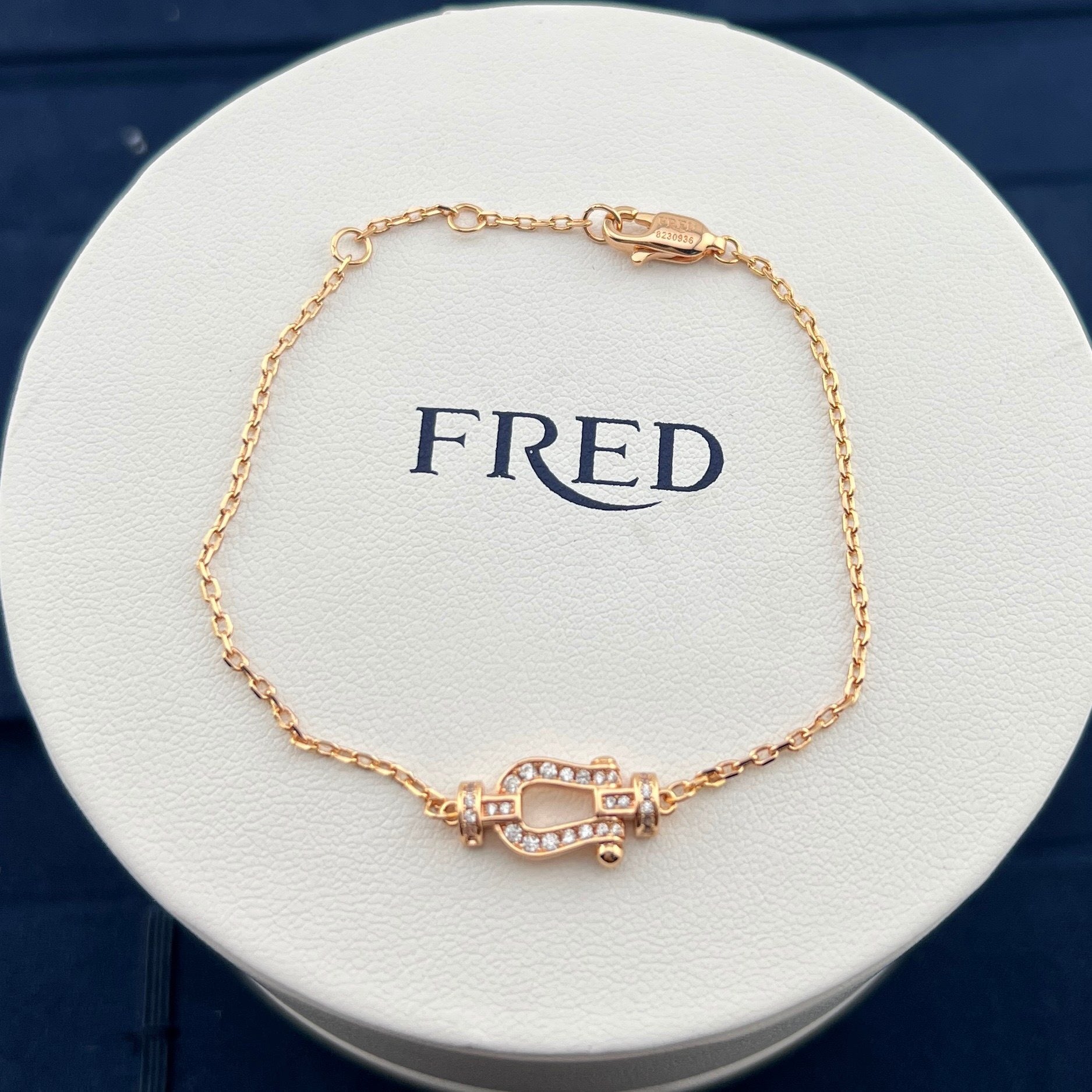 Gold bracelet on a white round display with 'FRED' branding