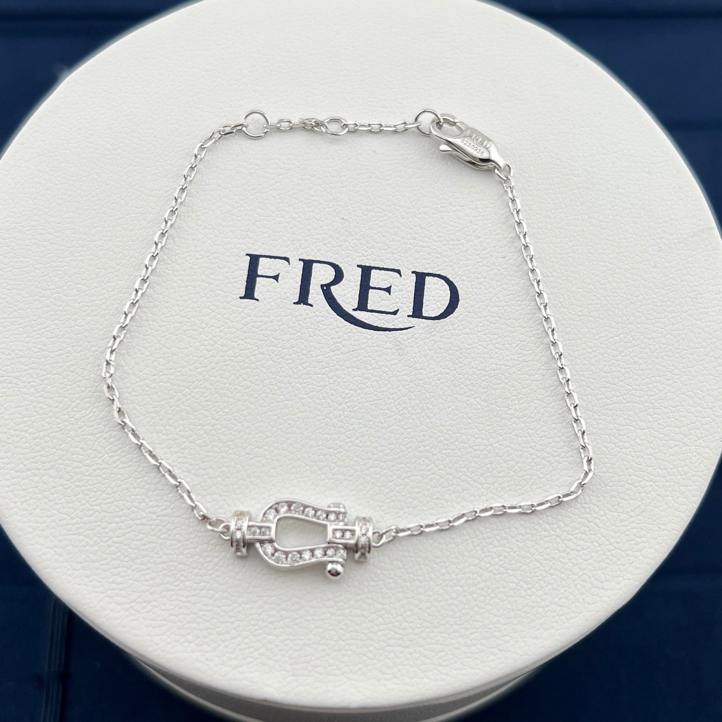 Silver bracelet on a white circular stand with 'FRED' branding