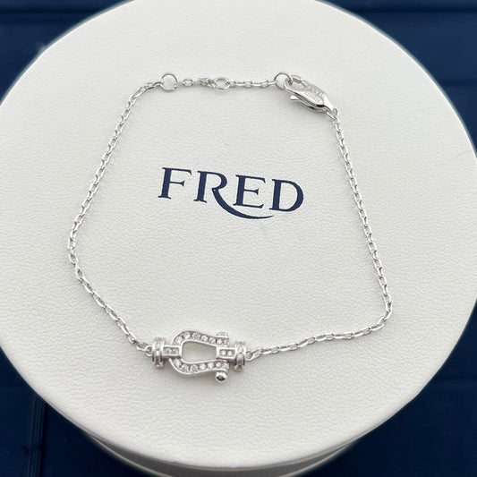 Silver bracelet on a white circular stand with 'FRED' branding