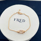 Gold bracelet on a white circular box with 'FRED' branding.
