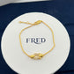 Gold bracelet on a white display card with 'FRED' branding.