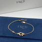 Gold bracelet with a clasp on a blue FRED branded surface