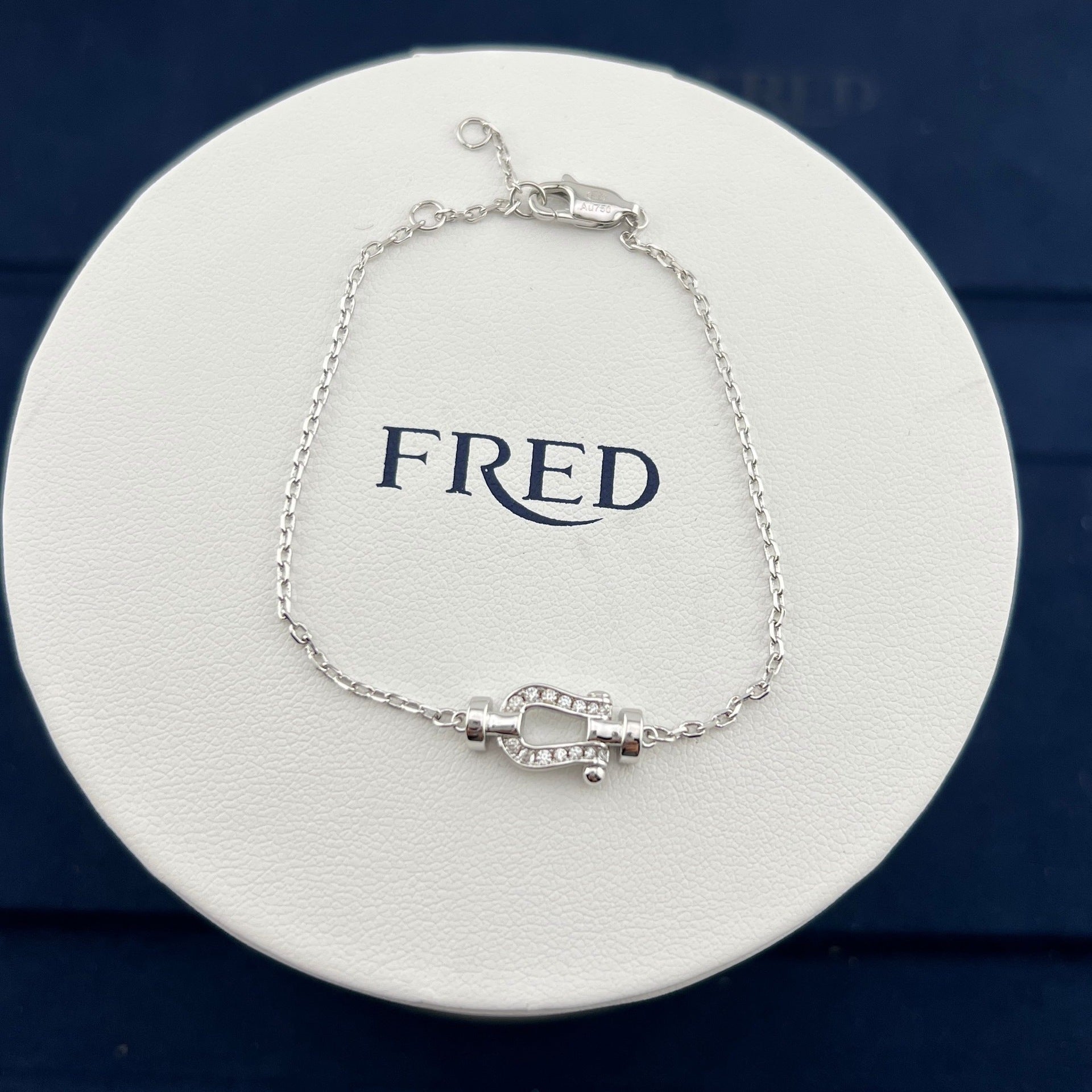 Silver bracelet on a white circular stand with 'FRED' branding.