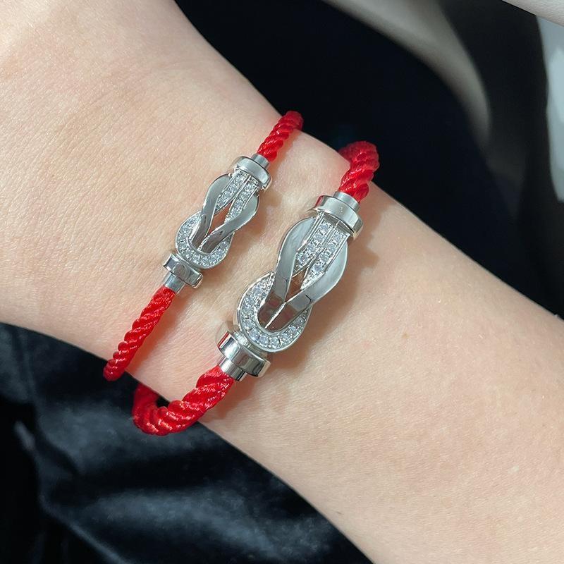 Force 10 bracelet 18k yellow gold and diamonds with diamond accents on a red cord worn on a wrist against a dark background