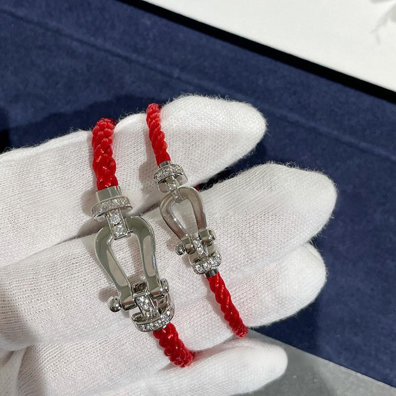 Force 10 bracelet 18k yellow gold and diamonds red strings on a white cloth background