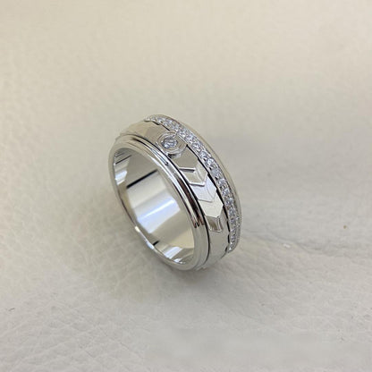 “Fortune Flow 925 sterling silver spinning ring with pavé zircons flat lay” Silver ring with intricate design on a light gray background