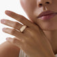 “Fortune Flow 925 sterling silver spinning ring with pavé zircons flat lay”Close-up of a woman's hand wearing a gold ring on a neutral background