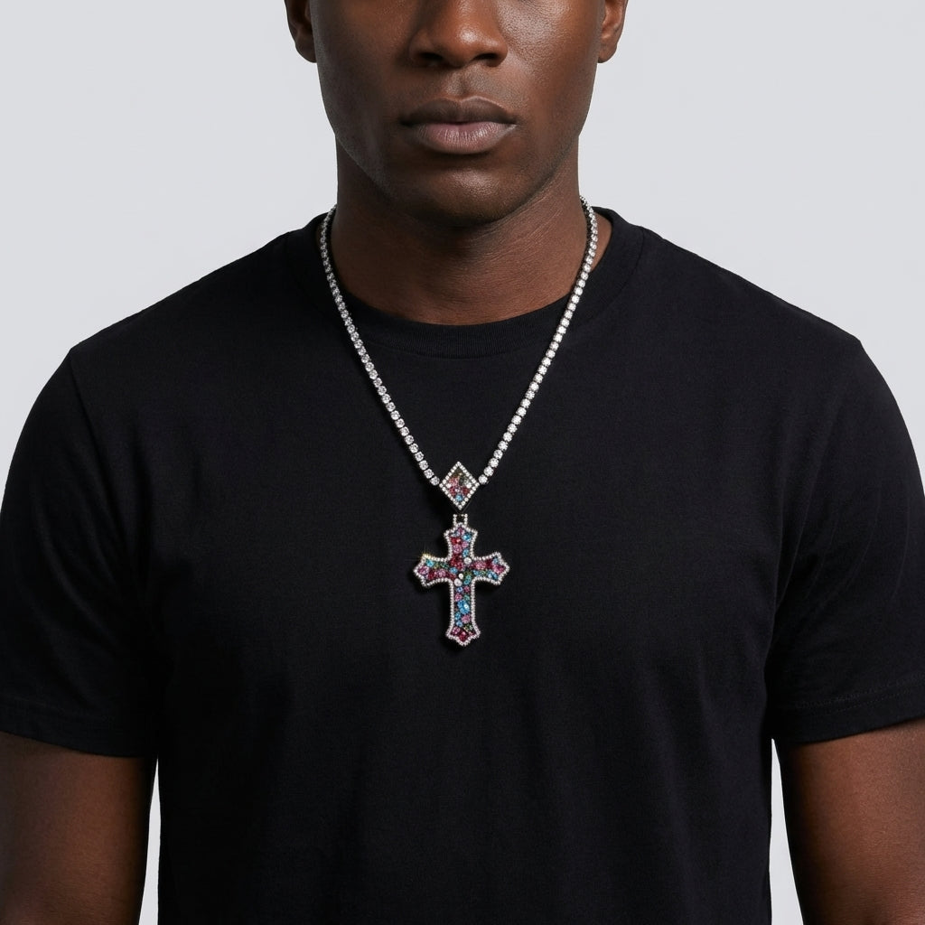 Man wearing a black t-shirt with a colorful cross pendant necklace on a plain background