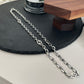 “Close-up of interlocking GG logo stations on Gucci silver necklace”