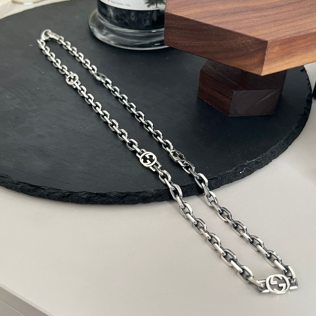 “Close-up of interlocking GG logo stations on Gucci silver necklace”