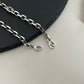 “Close-up of interlocking GG logo stations on Gucci silver necklace”
