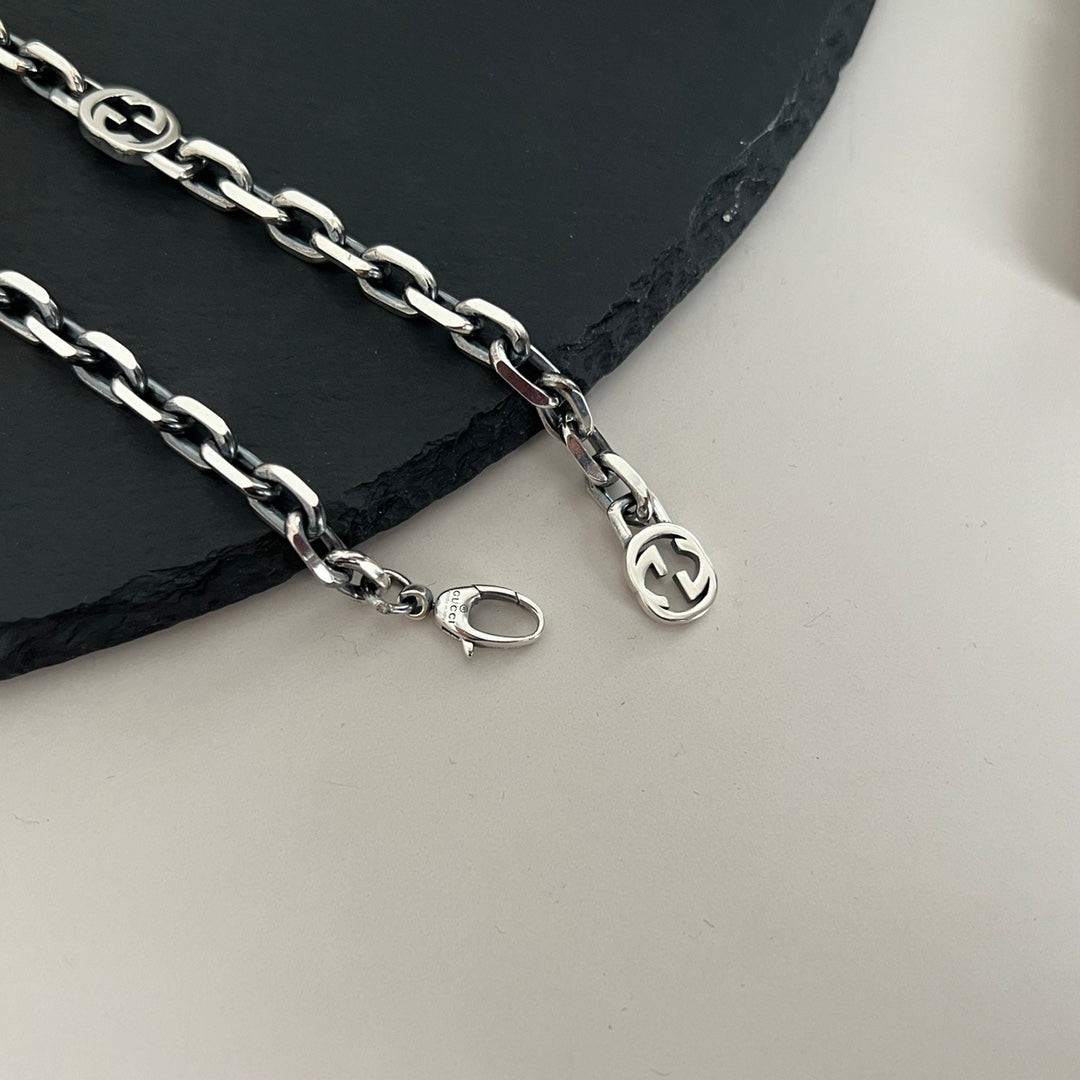 “Close-up of interlocking GG logo stations on Gucci silver necklace”
