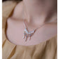 Necklace with a delicate design worn by a person against a neutral background