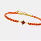 Bracelet with red and gold cord and a square gemstone on a white background