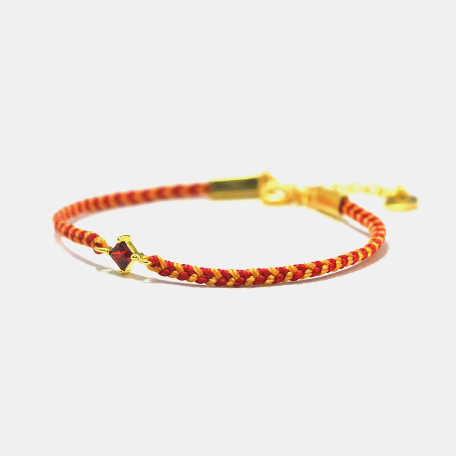 Bracelet with red and gold braided design on a white background