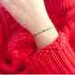 Close-up of a wrist wearing a green bracelet against a red textured fabric background