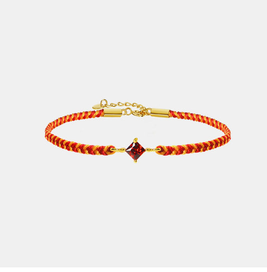 Bracelet with red and gold braided design and a square gemstone on a white background