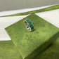 Gucci ring on a green patterned box with Gucci packaging in the background