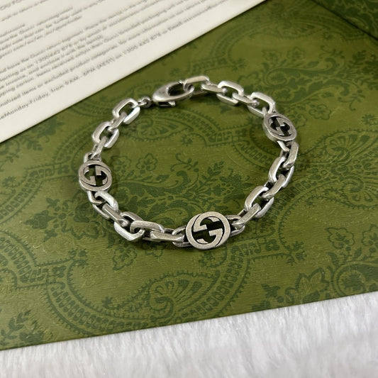 Gucci Interlocking chain bracelet with a Gucci logo on a green patterned surface