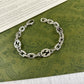 Gucci Interlocking chain braceletwith circular designs on a green patterned background