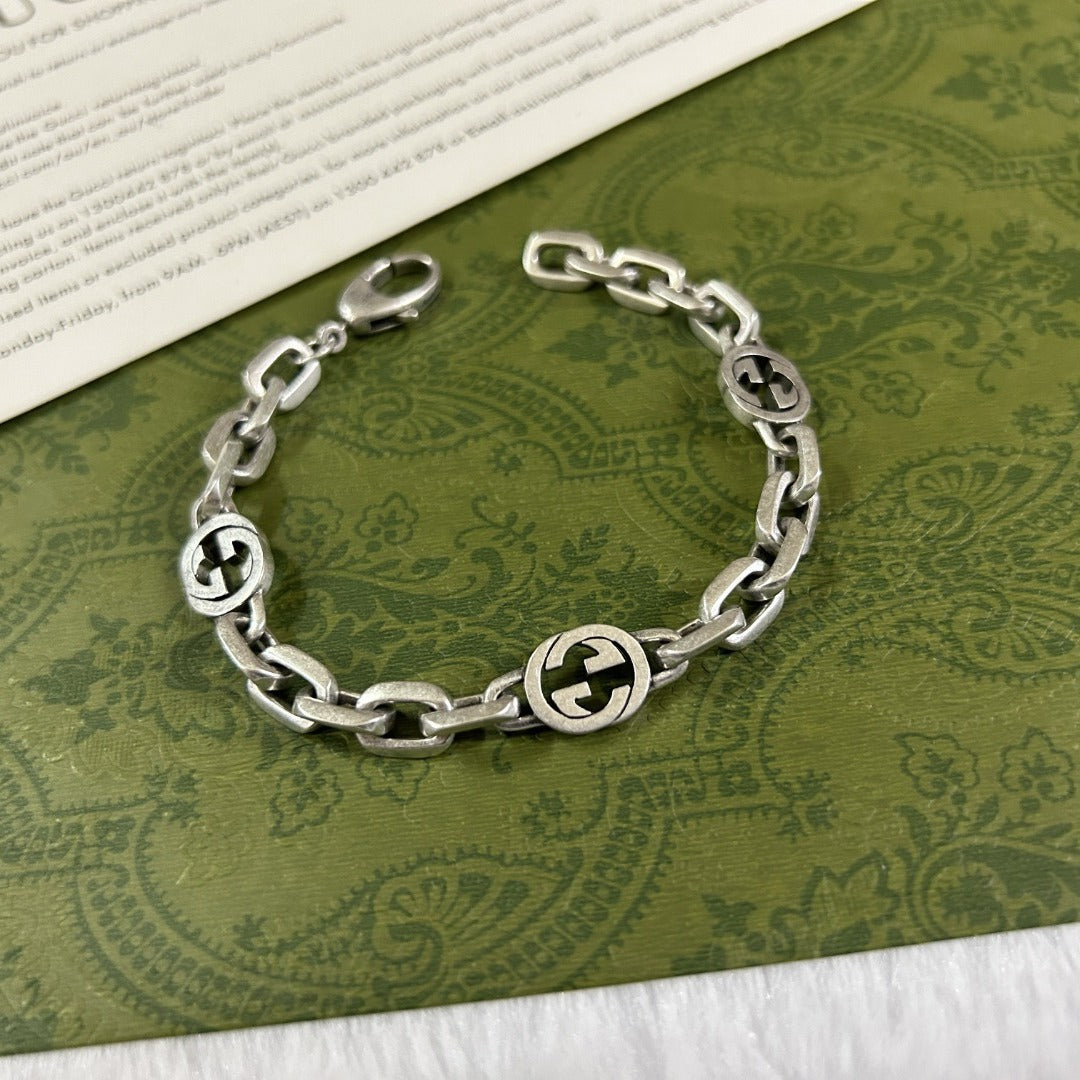 Gucci Interlocking chain braceletwith circular designs on a green patterned background