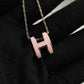 High-End “H” Enamel Pendant Necklace Necklace with a pink 'H' pendant on a black background
