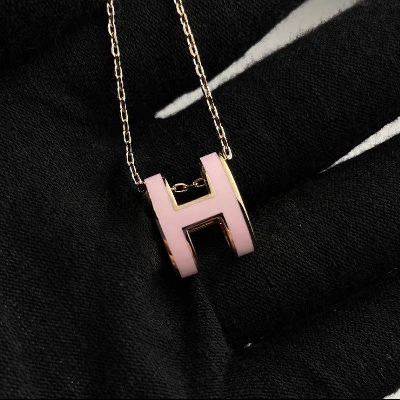 High-End “H” Enamel Pendant Necklace Necklace with a pink 'H' pendant on a black background