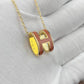 High-End “H” Enamel Pendant Necklace Gold and red necklace with a 'H' pendant on a white fabric background