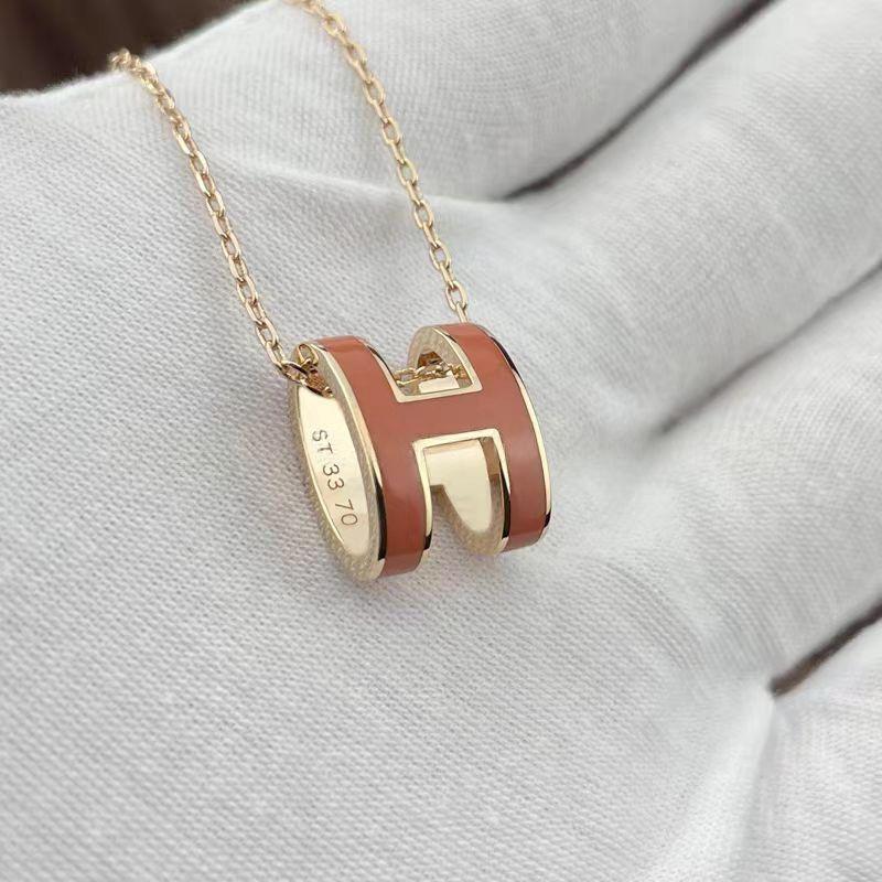 High-End “H” Enamel Pendant Necklace Gold and red 'H' pendant necklace on a light gray surface