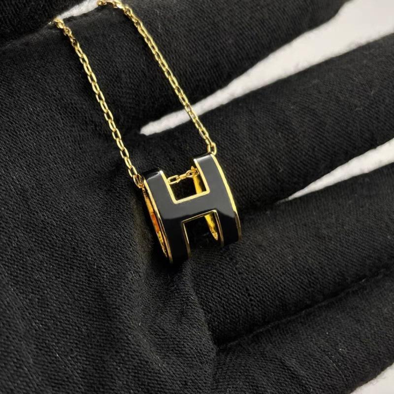 High-End “H” Enamel Pendant Necklace Gold and black letter 'H' necklace on a black background