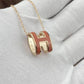 High-End “H” Enamel Pendant Necklace Gold and red 'H' pendant necklace on a light gray surface