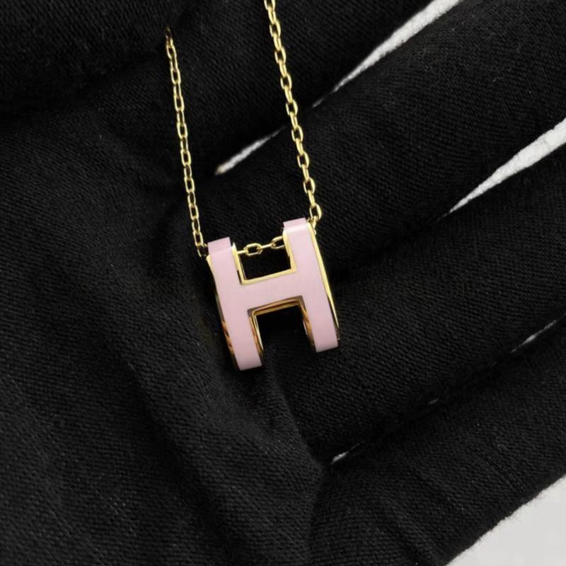 High-End “H” Enamel Pendant Necklace Necklace with a pink 'H' pendant on a black background