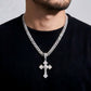 Man wearing a silver chain necklace with a cross pendant on a plain background