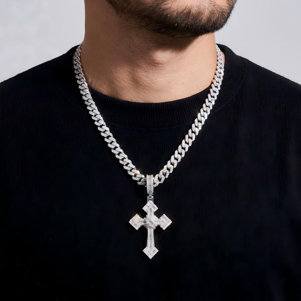 Man wearing a silver chain necklace with a cross pendant on a plain background