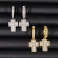 Cross-shaped earrings in gold and silver on a black textured background