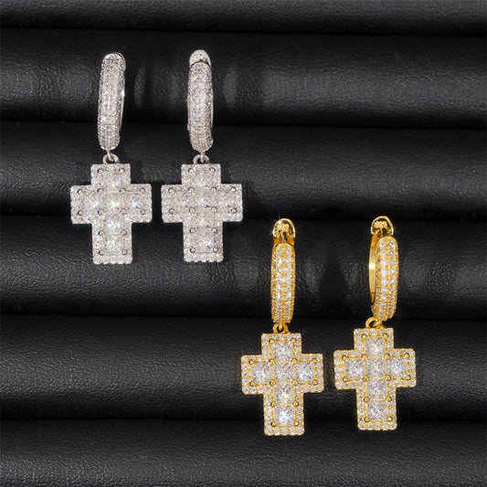 Cross-shaped earrings in gold and silver on a black textured background