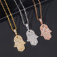 Three Hamsa hand pendants on chains in gold, silver, and rose gold on a dark background.