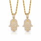 Two gold Hamsa hand pendants on chains against a white background