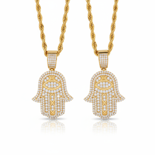 Two gold Hamsa hand pendants on chains against a white background
