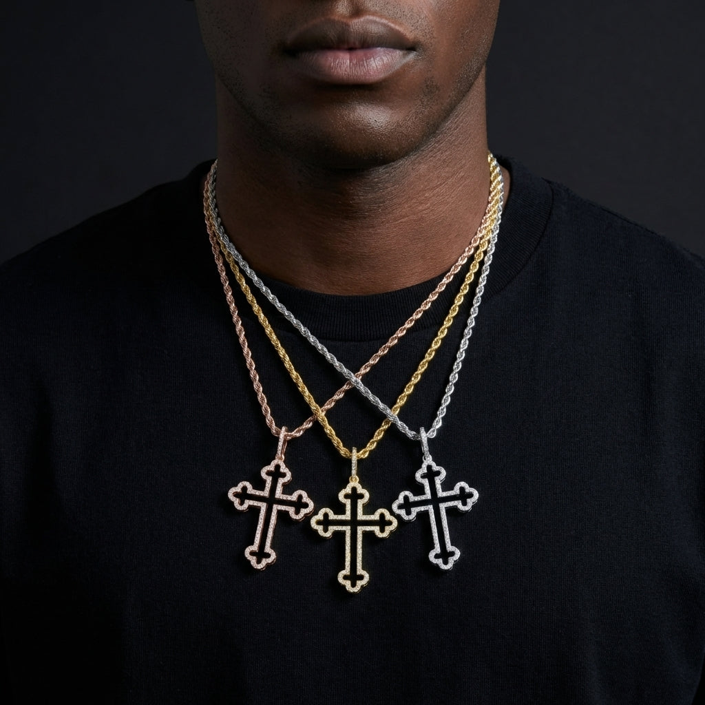Person wearing three cross-shaped pendants on gold chains against a dark background