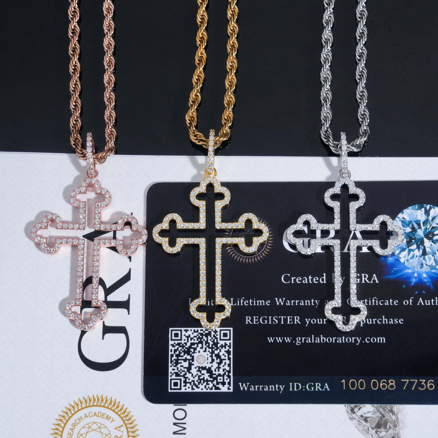 Three cross-shaped pendants on a card with GRA branding
