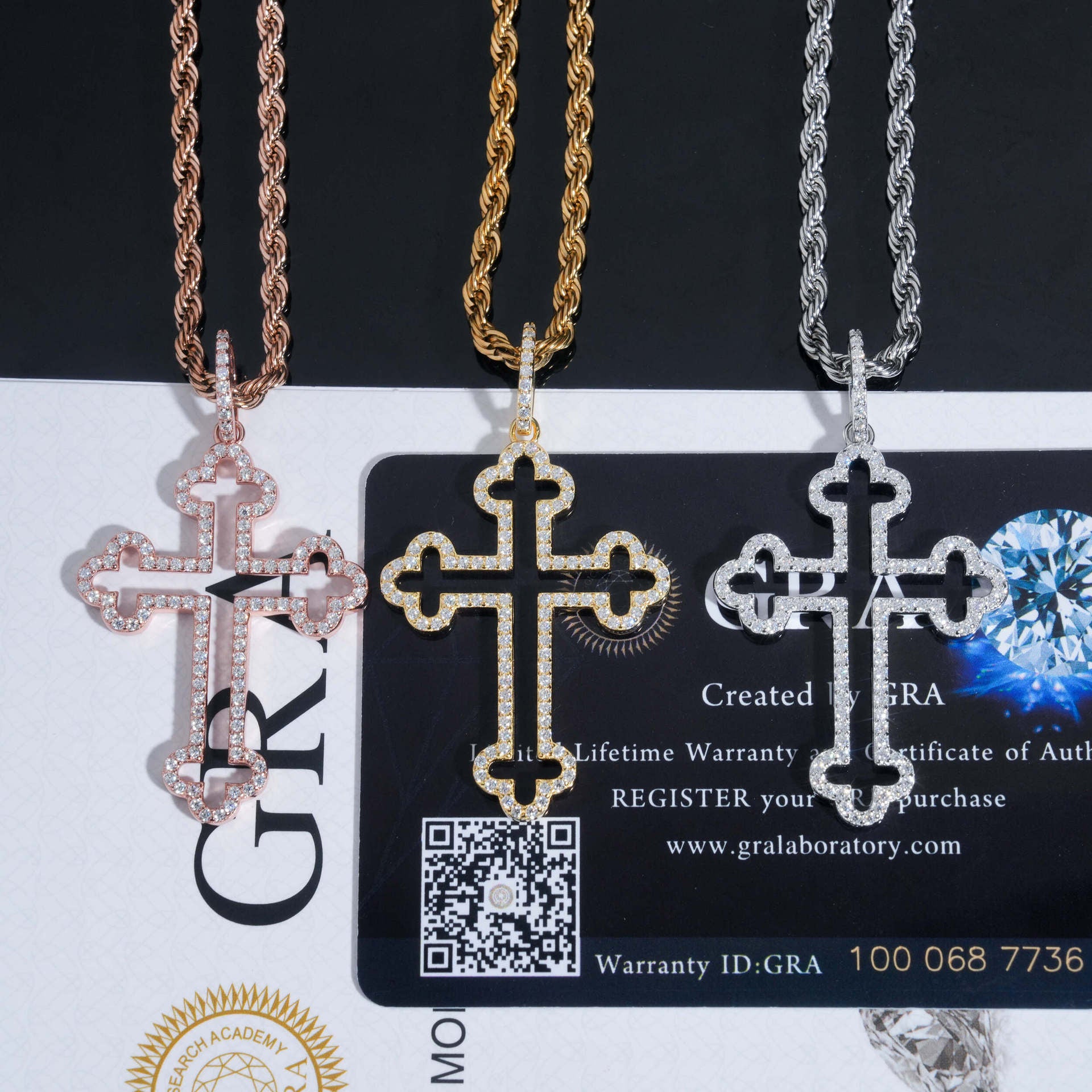 Three cross-shaped pendants on a card with GRA branding