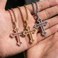 Three cross-shaped pendants on chains held in a hand.